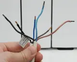 Main fil pilote noir, phase neutre et fils bleus et marron dénudés.
