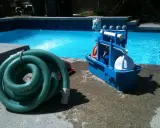 Tuyau vert enroulé et boîte bleue d'accessoires de nettoyage pour le branchement piscine.