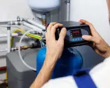 Un technicien ajuste un adoucisseur d'eau pour lutter contre la dureté de l'eau à Lille.
