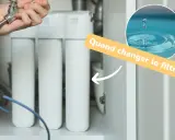 Main d'un homme tenant un robinet, avec un système de filtration d'eau et un texte "Quand changer le filtre ?". Un filtre adoucisseur bloqué peut causer des problèmes.