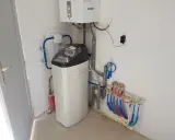 Installation d'un adoucisseur d'eau Comap, avec chaudière et tuyauterie. Un problème potentiel avec l'adoucisseur Comap est visible.