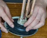 Mains de l'homme ajustant un élément chauffant entartré sur un joint plat, prêt pour le remplacement.