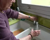 Une femme remplit un verre d'eau du robinet. L'eau de Beauvais coule fraîchement.