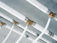 Système de tuyauterie blanche avec raccords en laiton, une installation multicouche complexe sous un plafond en béton.