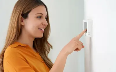 Une femme ajuste son cee thermostat connecté.