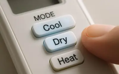 Doigt appuyant sur le bouton "Cool" d'une télécommande clim, offrant le choix entre clim heat ou cool.