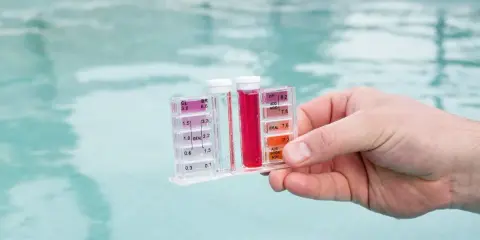 Testeur de piscine mesurant le chlore et le pH. La couleur rouge indique un niveau de chlore élevé, suggérant qu'il faut enlever le chlore de l'eau.