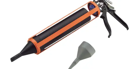 Pistolet à joint orange et noir, prêt à l'emploi pour vos travaux de calfeutrage. Un embout gris est également visible.