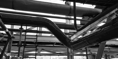 Gros plan sur des tuyaux industriels, certains recouverts d'une texture rugueuse suggérant un colmatage ou une isolation.