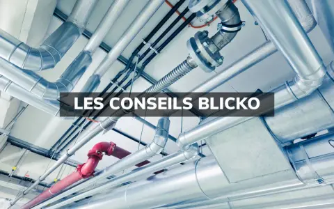 Un réseau complexe de tuyaux argentés et un tuyau rouge, installés au plafond. Ces tuyaux semblent cacher des secrets techniques.
