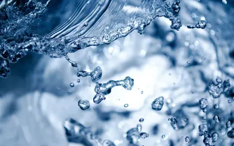 Éclaboussures d'eau bleue, évoquant la dureté de l'eau à Rennes. Des gouttelettes figées dans l'air, capturant le mouvement dynamique.