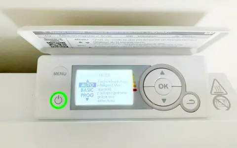 Thermostat sur radiateur électrique. L'écran affiche "MODE AUTO" pour un pilotage intelligent. Le bouton d'alimentation est allumé en vert.