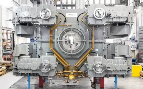 Gros équipement industriel gris avec des tuyaux orange, un ventilateur central et des éléments circulaires. Il s'agit d'un joint SMS, prêt pour l'assemblage.
