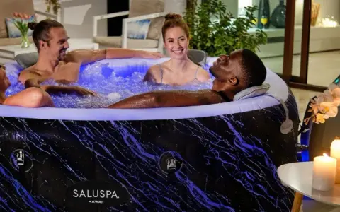 Quatre amis profitent d'un moment de détente dans un spa gonflable, illuminé de bleu. L'entretien de ce spa gonflable est simple pour des moments de pur bonheur.