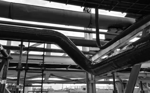 Gros plan sur des tuyaux industriels, certains recouverts d'une texture rugueuse suggérant un colmatage ou une isolation.