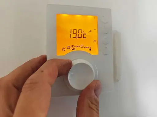 Main tenant ajuste le thermostat pour un mode confort, affichant 19.0°C.