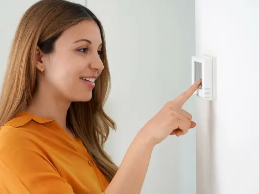 Une femme ajuste son cee thermostat connecté.