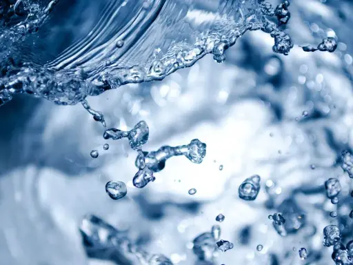 Éclaboussures d'eau bleue, évoquant la dureté de l'eau à Rennes. Des gouttelettes figées dans l'air, capturant le mouvement dynamique.