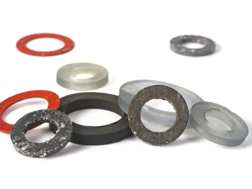 Ensemble de rondelles de différentes tailles et couleurs, dont un joint moulé rouge, gris et noir, sur fond blanc.