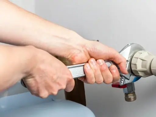 Mains d'un technicien serrant un raccord de tuyau lors d'un entretien adoucisseur d'eau Culligan.