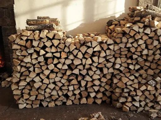 Gros tas de bois de chauffage empilés, prêts à être utilisés dans la cheminée. L'image montre une grande quantité de bois coupé, parfait pour stocker le bois de chauffage.