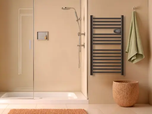 Salle de bain moderne avec douche, porte-serviettes chauffant noir et panier en liège. Le disjoncteur du sèche serviette est visible.