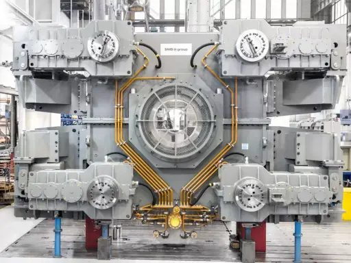 Gros équipement industriel gris avec des tuyaux orange, un ventilateur central et des éléments circulaires. Il s'agit d'un joint SMS, prêt pour l'assemblage.