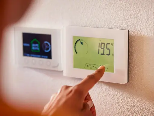 Main d'une personne ajustant un thermostat intelligent, symbole de la domotique sans fil. Confort et efficacité énergétique à portée de main.