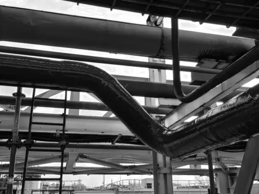 Gros plan sur des tuyaux industriels, certains recouverts d'une texture rugueuse suggérant un colmatage ou une isolation.