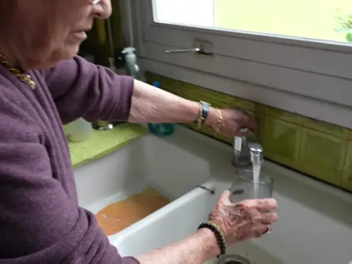 Une femme remplit un verre d'eau du robinet. L'eau de Beauvais coule fraîchement.