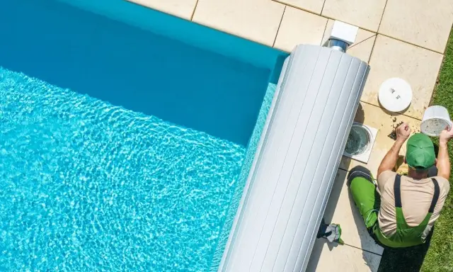 Un technicien nettoie le filtre de la pompe de piscine, un entretien essentiel pour optimiser la consommation d'énergie.