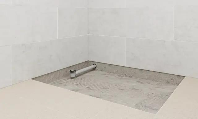 Installation d'un receveur de douche : un siphon est posé sur une chape avant le carrelage.