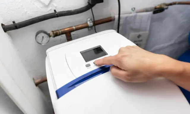 Main d'une personne appuyant sur le bouton "SET" d'un adoucisseur d'eau. Le manomètre indique la pression. Le 16 c'est quoi ?