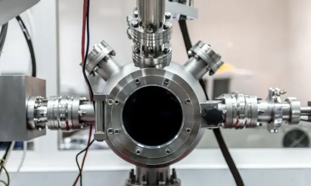 Gros plan sur un équipement de laboratoire complexe, avec une bride tournante inox au centre, connectée à divers tuyaux et raccords métalliques.