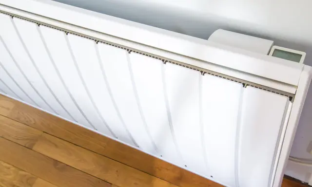 Radiateur électrique blanc installé sur un parquet. Un écran affiche la température. Guide pour comment installer un radiateur électrique.