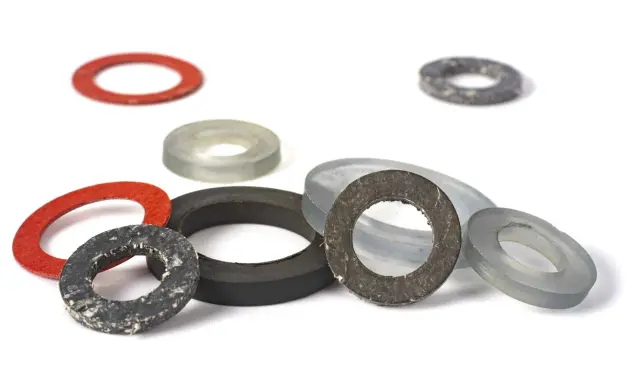 Ensemble de rondelles de différentes tailles et couleurs, dont un joint moulé rouge, gris et noir, sur fond blanc.