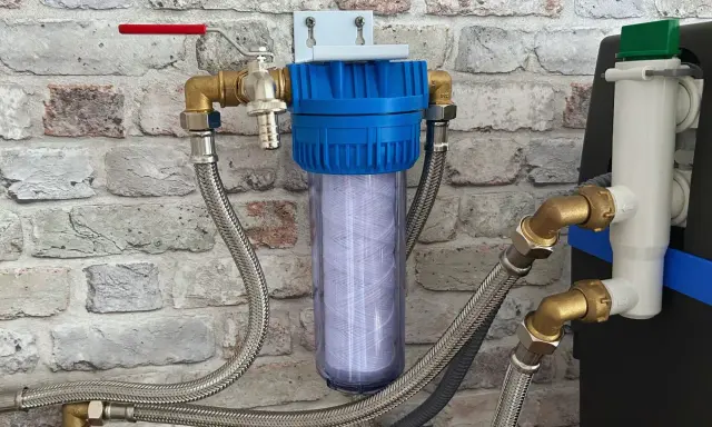 Système de filtration d'eau avec cartouche visible, raccordé à un adoucisseur. Un filtre avant adoucisseur obligatoire pour une eau pure.