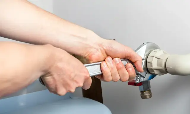 Mains d'un technicien serrant un raccord de tuyau lors d'un entretien adoucisseur d'eau Culligan.