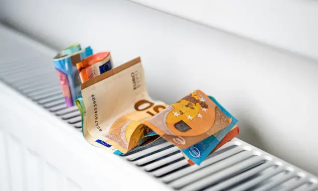 Des billets en euros pliés sur un radiateur blanc, symbolisant le coût élevé du chauffage et la **consommation** du **radiateur hors gel**.