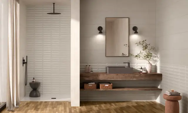Une **salle de bain moderne** avec un sol en bois, une douche à l'italienne, un lavabo suspendu et un miroir.