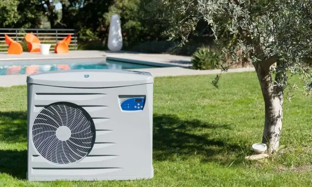 Pompe à chaleur pour piscine, élément clé d'un schéma de filtration performant, installée sur une pelouse verdoyante près d'une piscine.