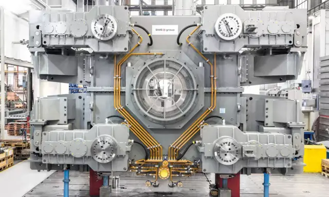 Gros équipement industriel gris avec des tuyaux orange, un ventilateur central et des éléments circulaires. Il s'agit d'un joint SMS, prêt pour l'assemblage.
