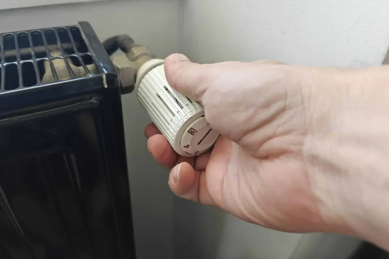 Main tenant ajuste le thermostat pour savoir quand éteindre le chauffage.