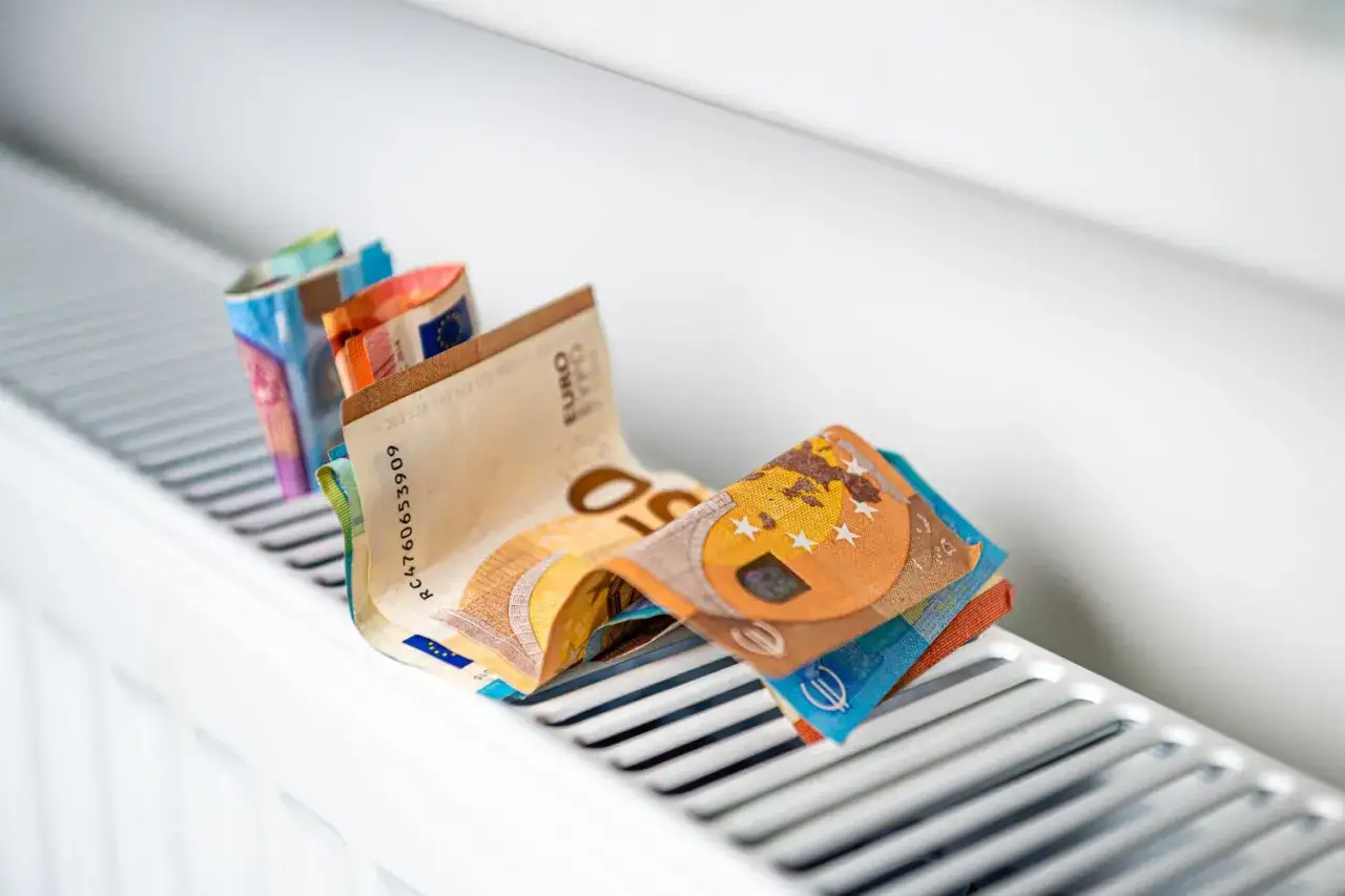 Des billets en euros pli&eacute;s sur un radiateur, symbolisant le co&ucirc;t &eacute;lev&eacute; du chauffage et la consommation.