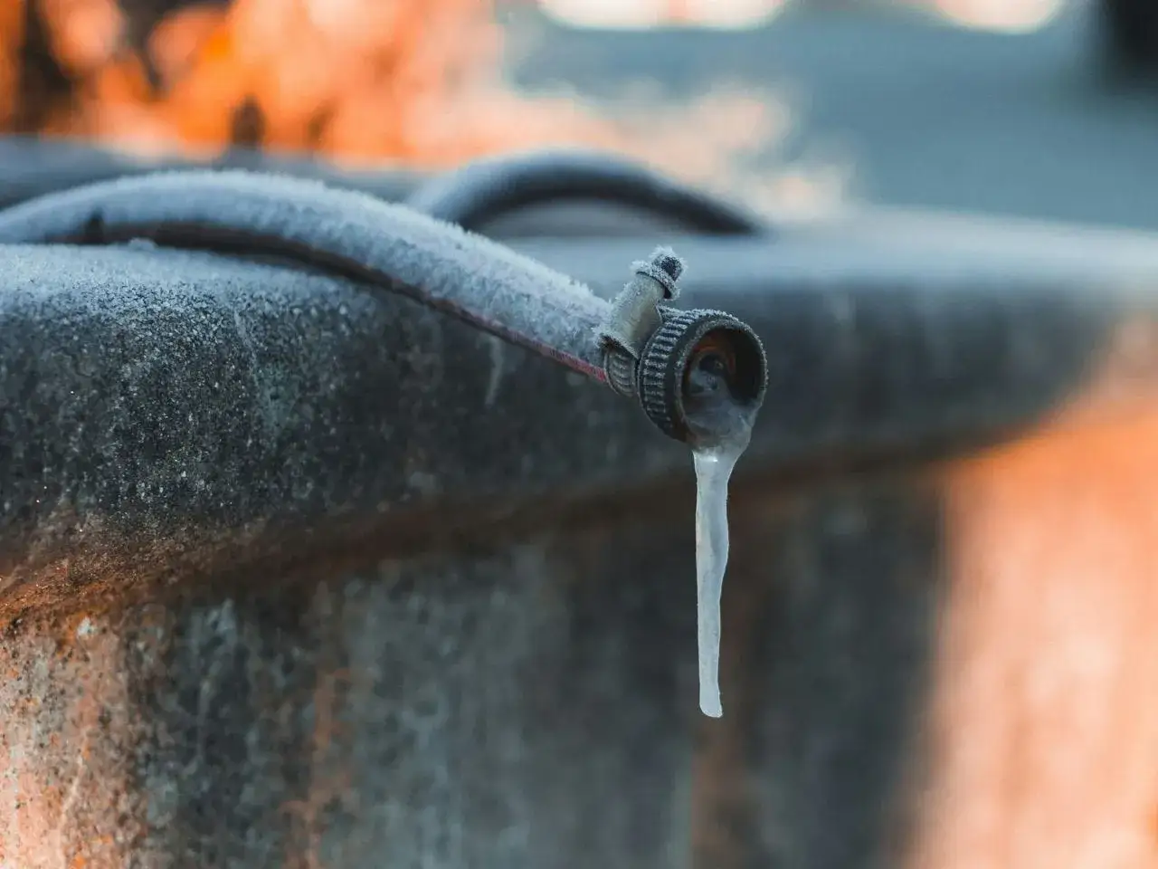 Un tuyau de jardin givré avec une stalactite de glace pendante. La protection tuyau est essentielle pour éviter ce genre de dégâts en hiver.