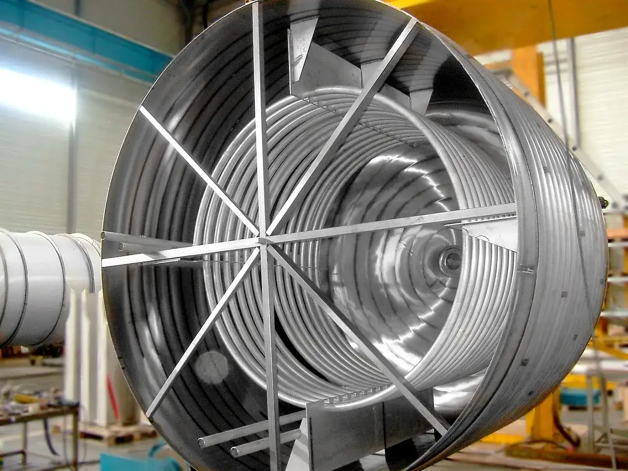 Intérieur d'un grand échangeur de chaleur industriel avec un serpentin métallique en spirale, prêt pour le transfert de fluides.