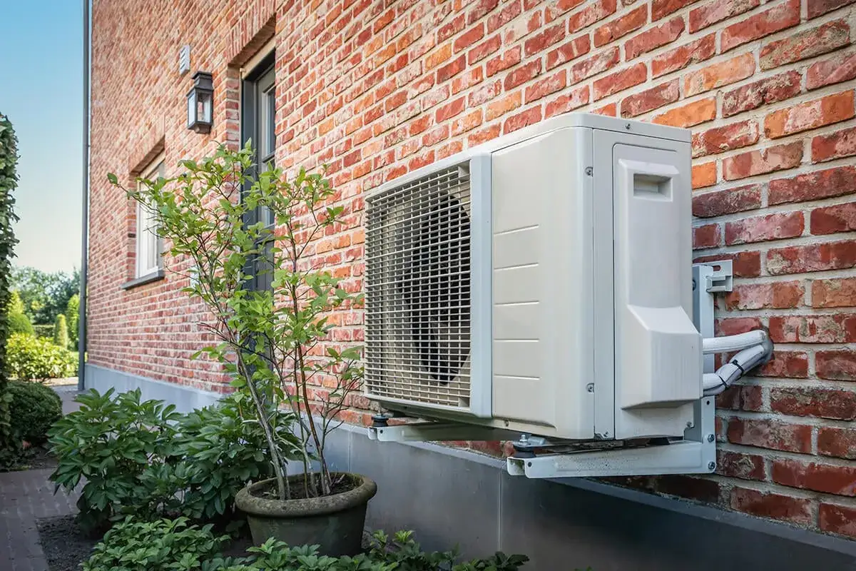 Unité extérieure de climatisation fixée au mur de briques. Le cop pac air air assure un confort thermique optimal.
