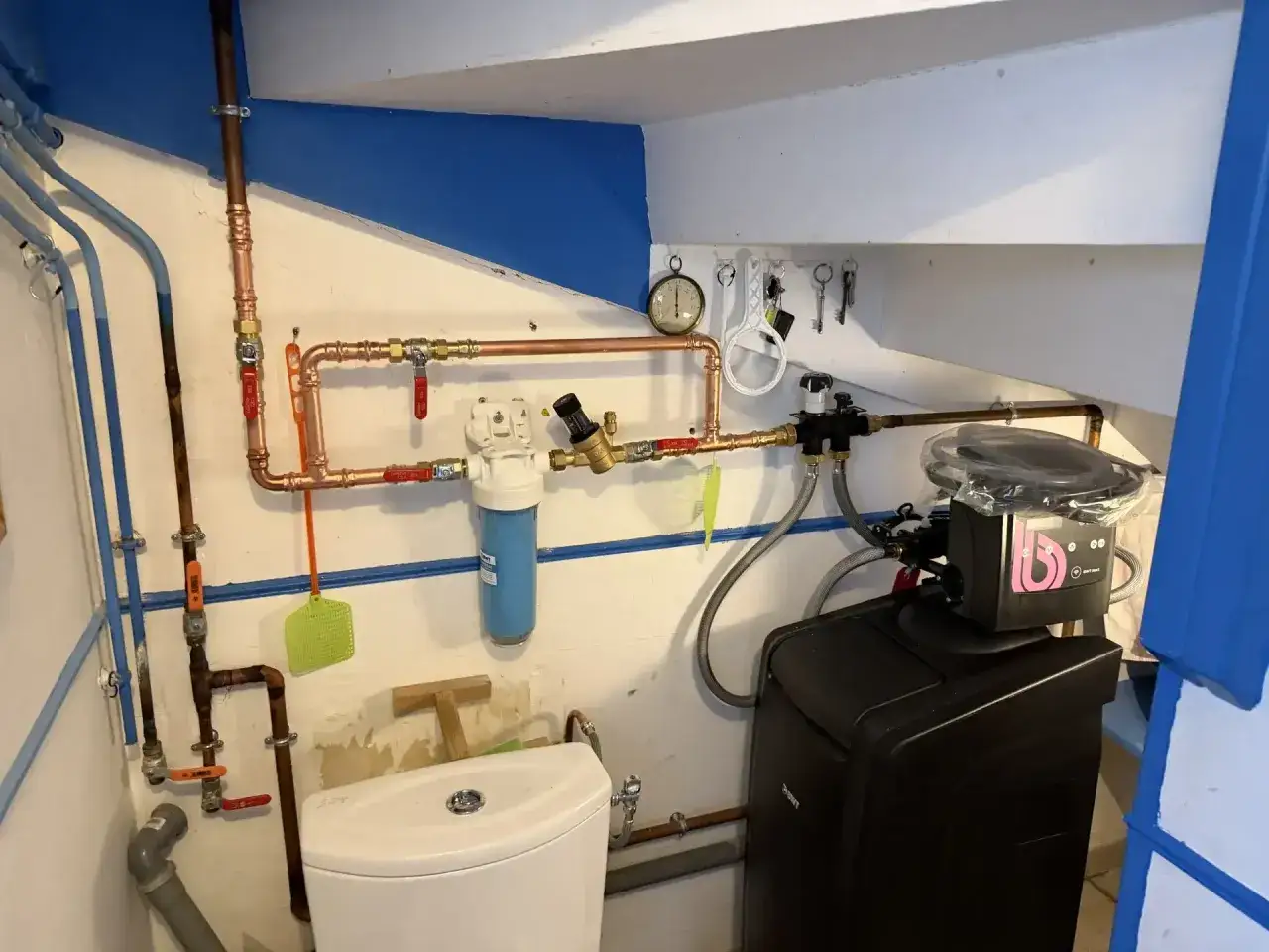 Installation d'un système de filtration d'eau et d'un adoucisseur d'eau, avec tuyauterie en cuivre et un réservoir noir.