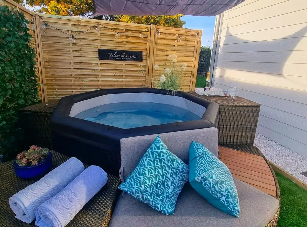 Ambiance relaxante autour d'un spa gonflable : coussins bleus, serviettes douces, guirlande lumineuse et une touche de champagne pour une soirée parfaite.