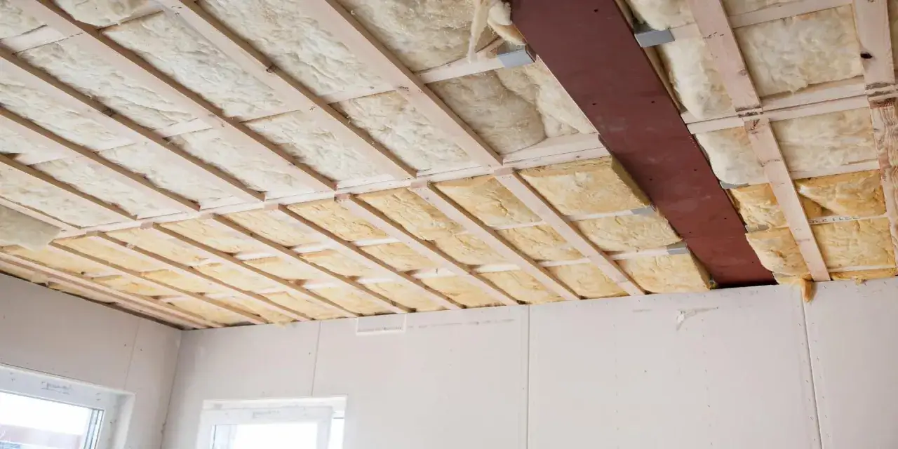 Travaux d'isolation thermique plafond en cours, avec laine de roche insérée entre les solives en bois.